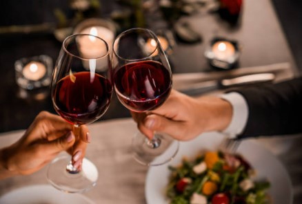 stukające się dwa kieliszki czerwonego wina na randce w niezapomniane walentynki