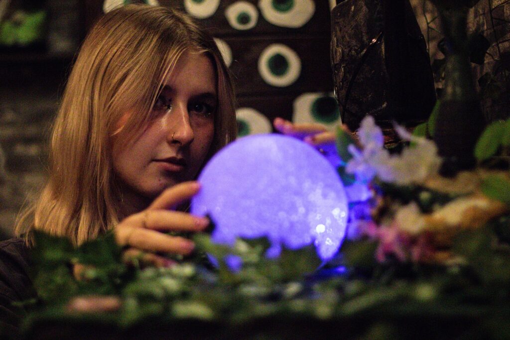 na zdjeciu kobieta przy swiecacej krysztalowej kuli, zagadki do escape room w domu dla dzieci